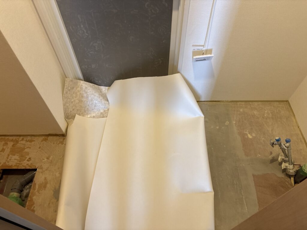 Vinyl flooring sheet positioned in the bathroom before flooring adhesive is applied.