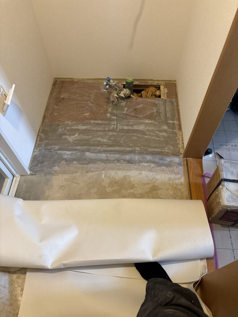 Worker applying adhesive to the floor before installing vinyl flooring.