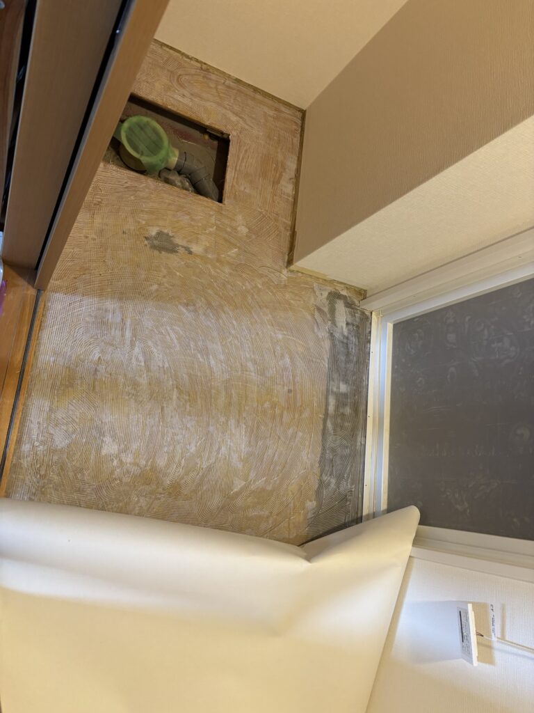 Worker installing vinyl flooring in a bathroom vanity area.