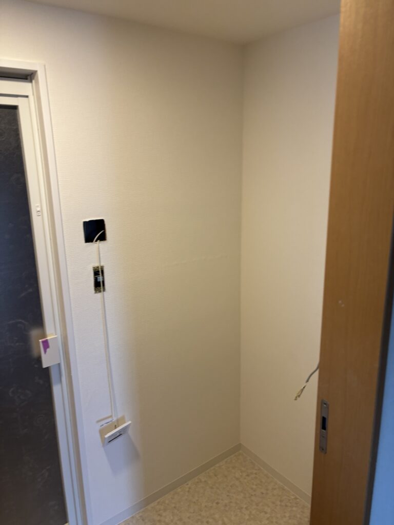 Completed bathroom vanity and laundry area with new wallpaper, vinyl flooring, and soft baseboards.