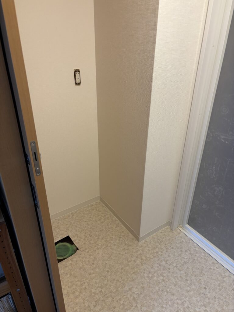 Final completed bathroom renovation with new wallpaper, vinyl flooring, and soft baseboards after cleanup.