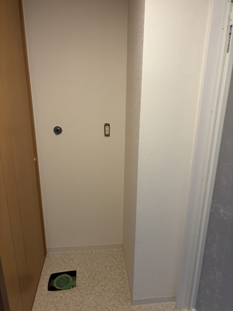 Completed bathroom vanity and laundry area with new wallpaper, vinyl flooring, and soft baseboards.