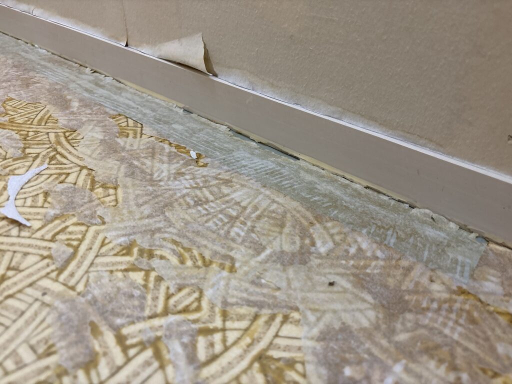 Gap underneath the wooden baseboard after removing one layer of old vinyl flooring