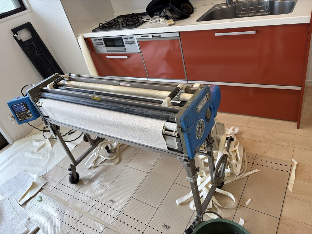 Long wallpaper being prepared with a wallpaper pasting machine for ceiling installation.