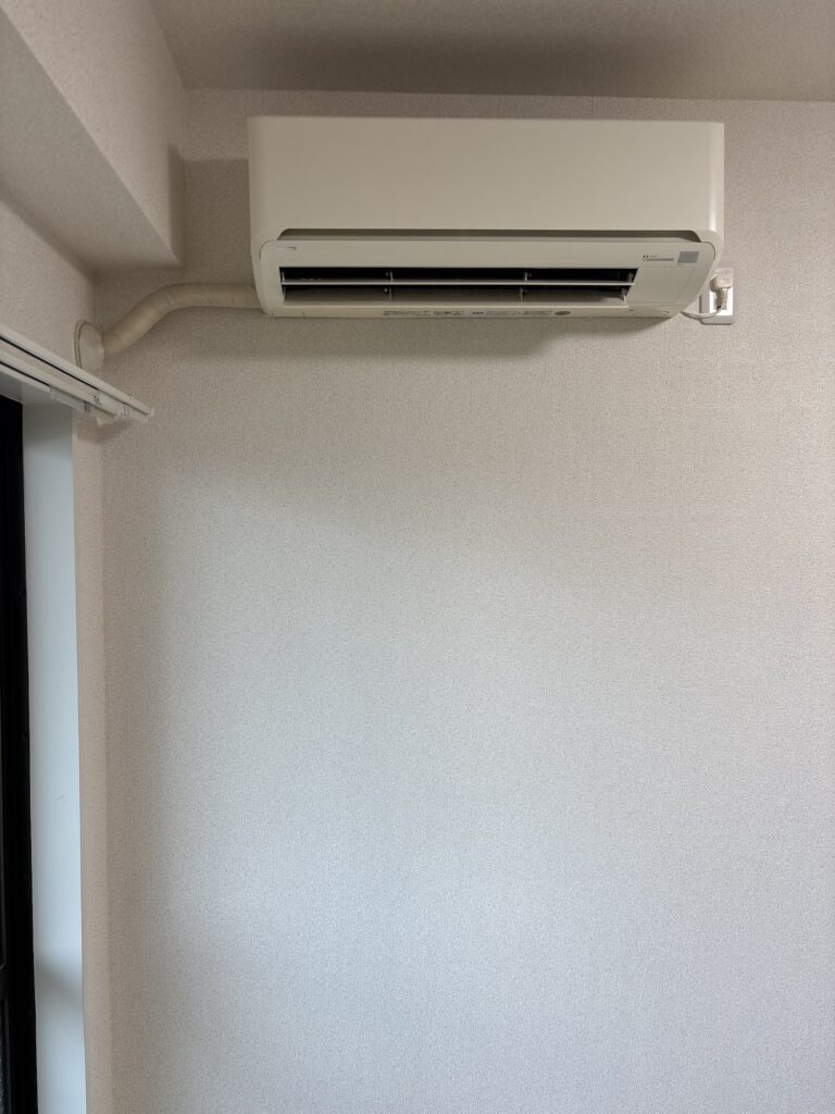 Completed wallpaper installation around an existing air conditioner and pipes.