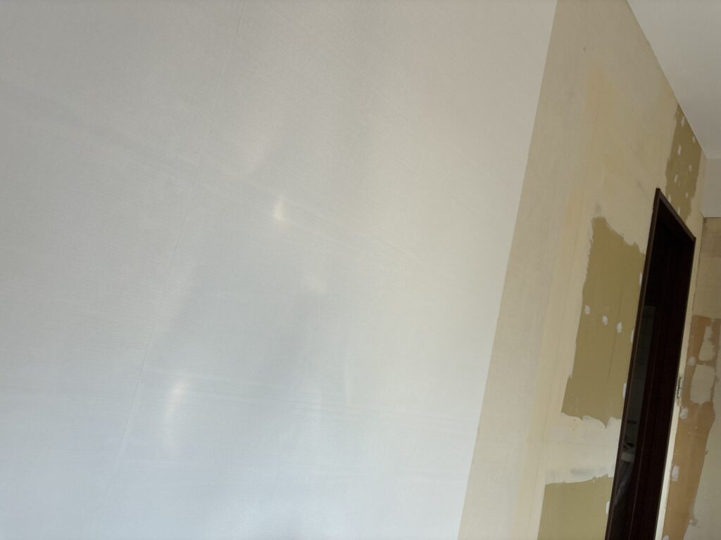 White wallpaper being installed on a living room wall