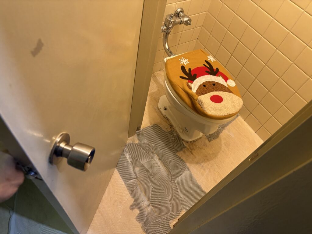 Adhesive being evenly applied to the toilet floor before cushion flooring installation