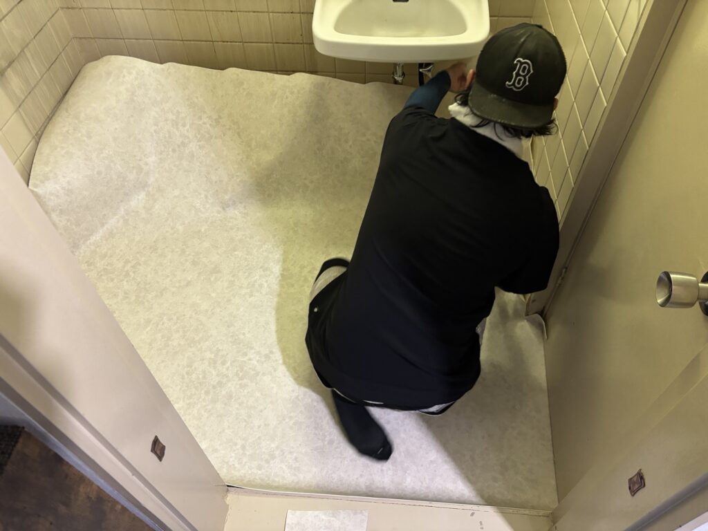 One-piece cushion flooring being installed in a condominium washroom