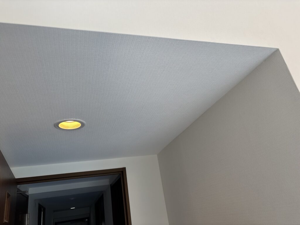 Completed wallpaper installation on a dropped ceiling in the living room