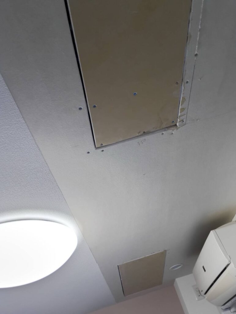 Living room ceiling before partial wallpaper replacement in a Japanese apartment