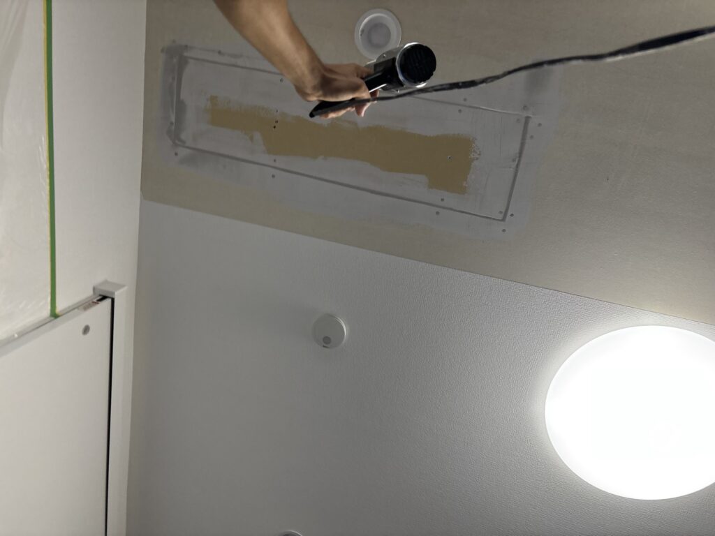 Using a heat gun to dry joint compound on a living room ceiling