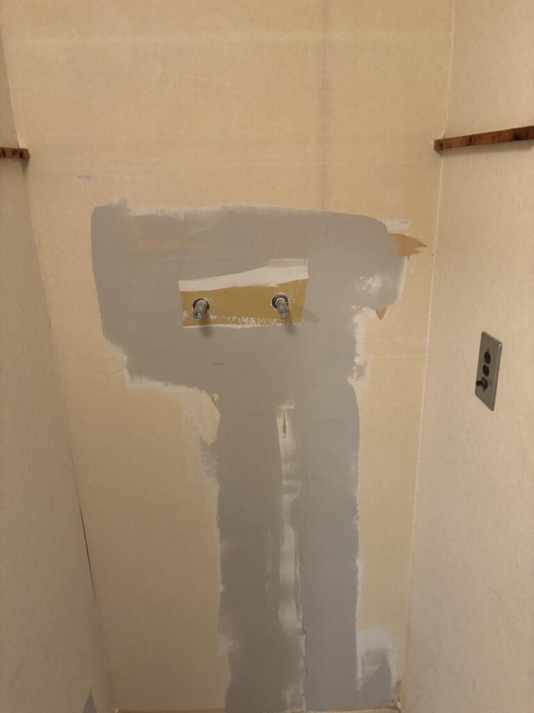 Base joint compound applied to repaired gypsum board before wallpaper installation