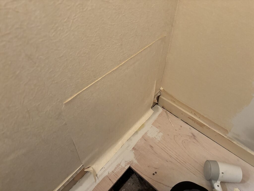 Reused wallpaper piece being installed on a repaired wall beside the washing machine area