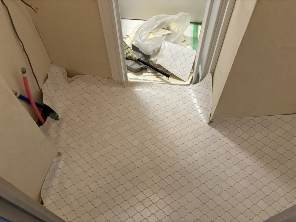 Patterned cushion flooring being installed and aligned in a Japanese apartment washroom