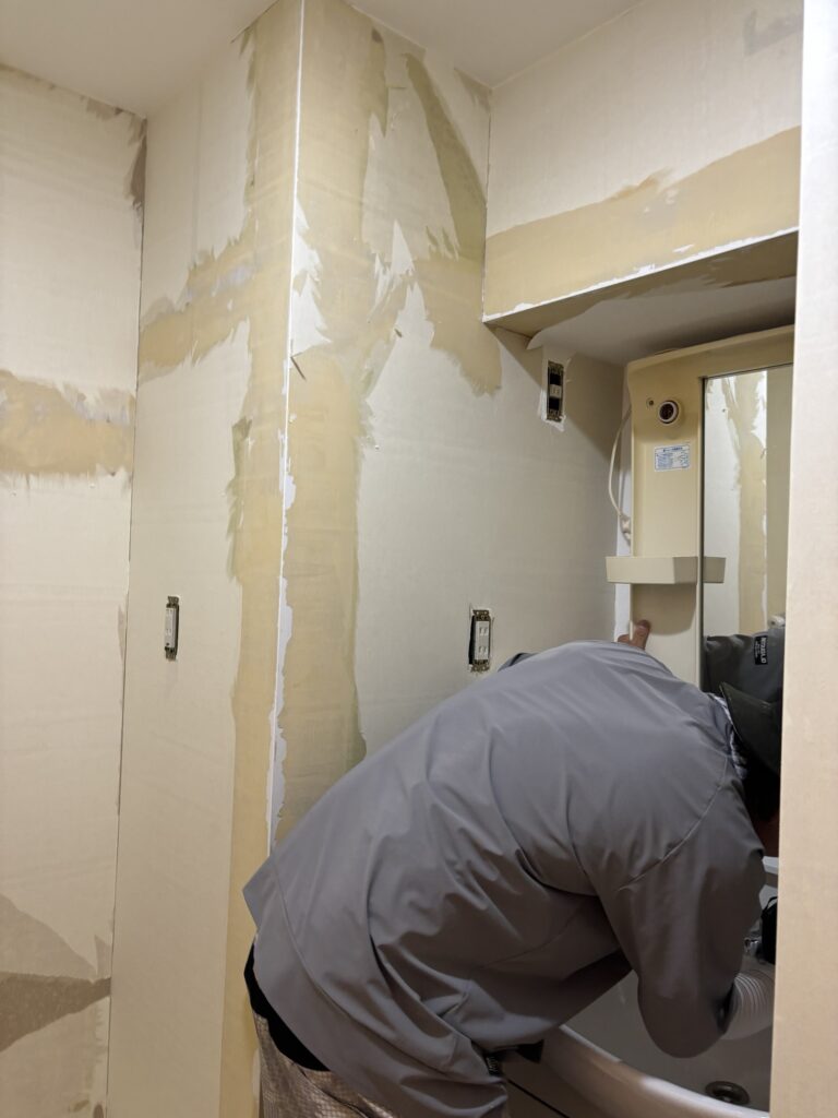 Worker removing a mirror above a washbasin before wallpaper installation