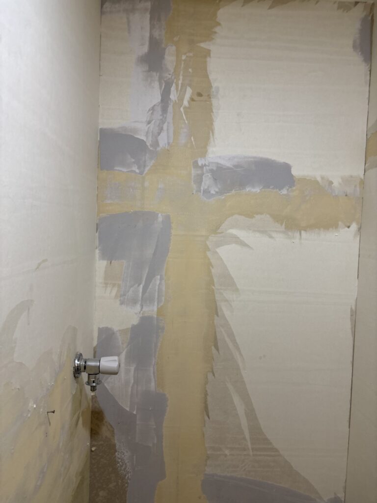 Base putty applied to a deteriorated washroom wall substrate