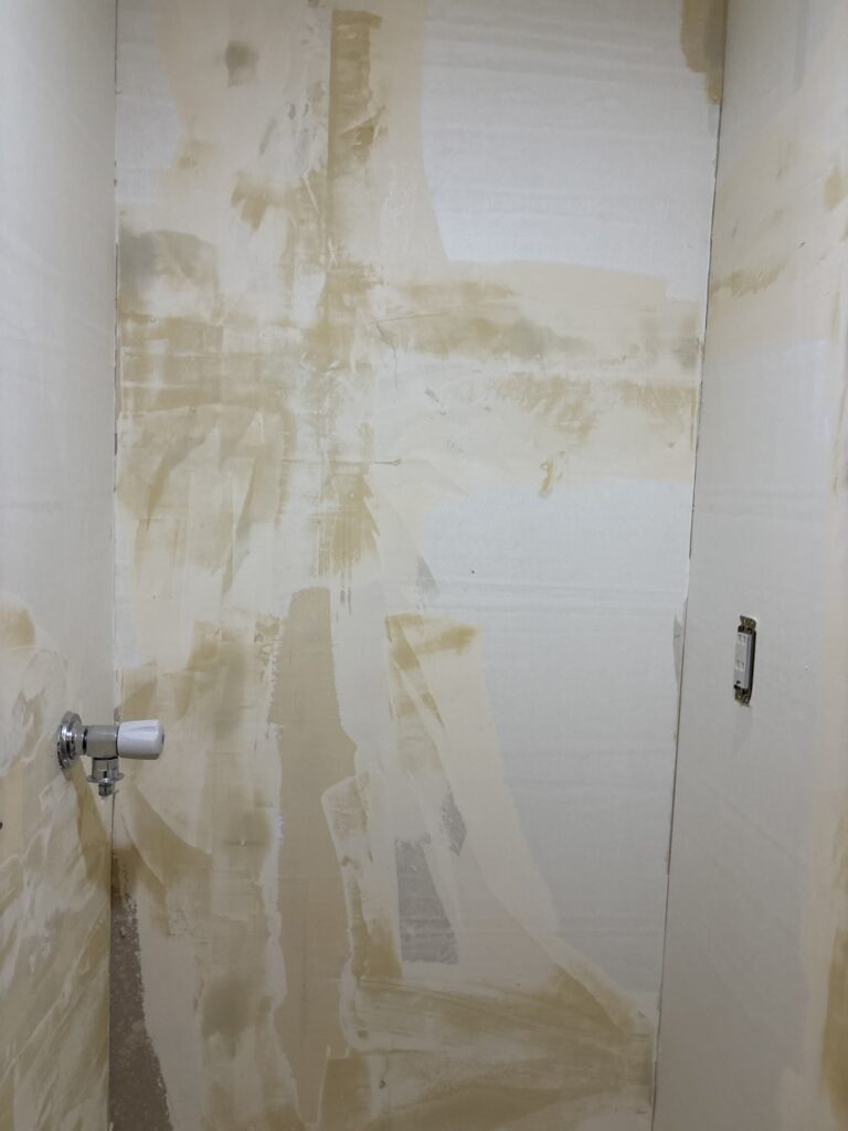 Finishing putty applied to a prepared washroom wall before wallpaper installation