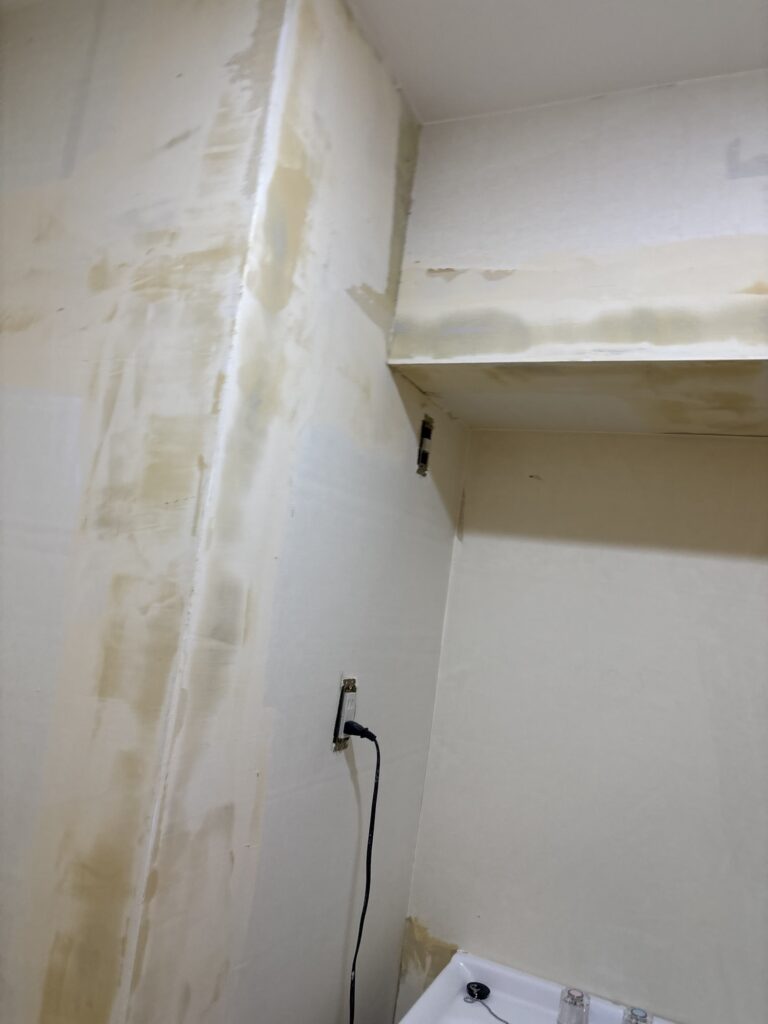 Washroom wall after finishing putty was applied before wallpaper installation