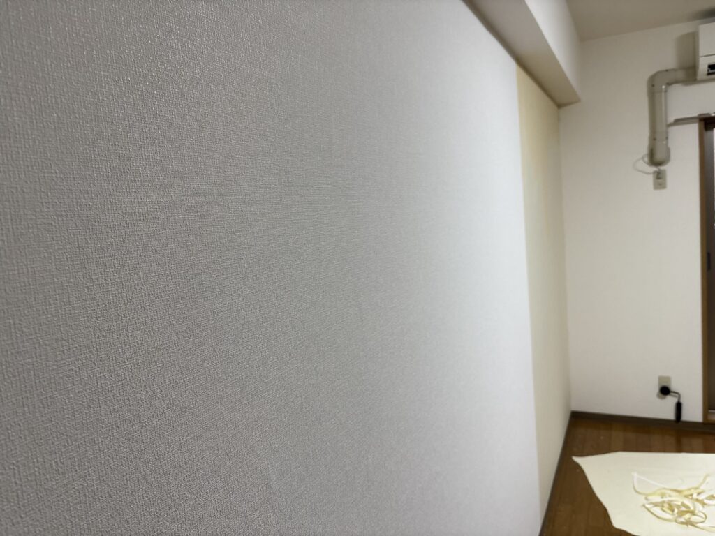 Worker installing white embossed wallpaper on a living room wall