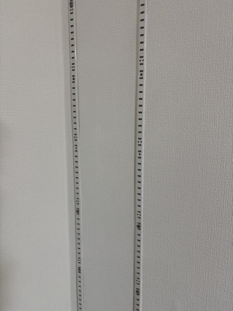 Wallpaper installation around an existing adjustable wall rail on a concrete wall