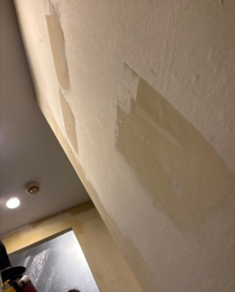 Completed stone-textured wallpaper installation on the kitchen ceiling, showing a clean and even finished surface around the ceiling fixtures.