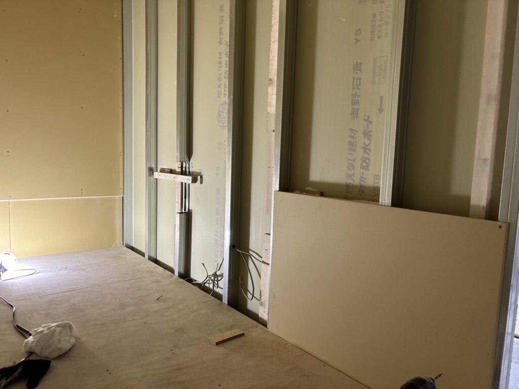 A worker installing a gypsum board panel on an interior wall during hotel renovation.