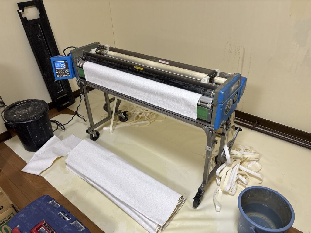 Wallpaper being prepared with a wallpaper pasting machine for ceiling installation