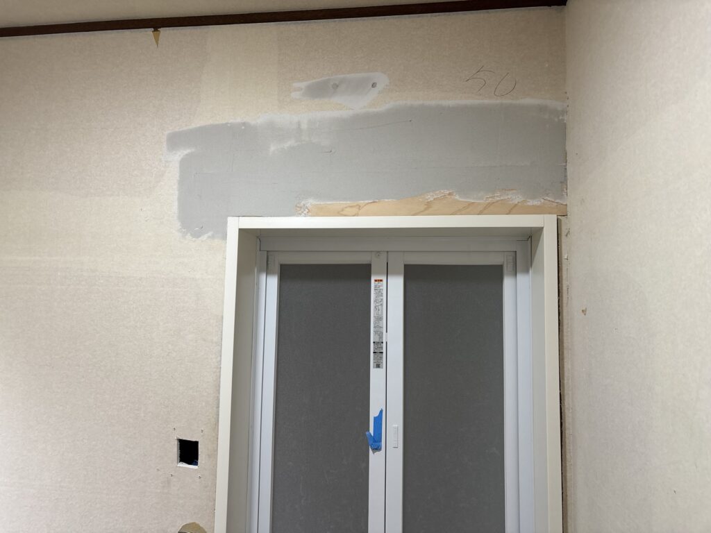 First coat of joint compound applied above the bathroom door frame.