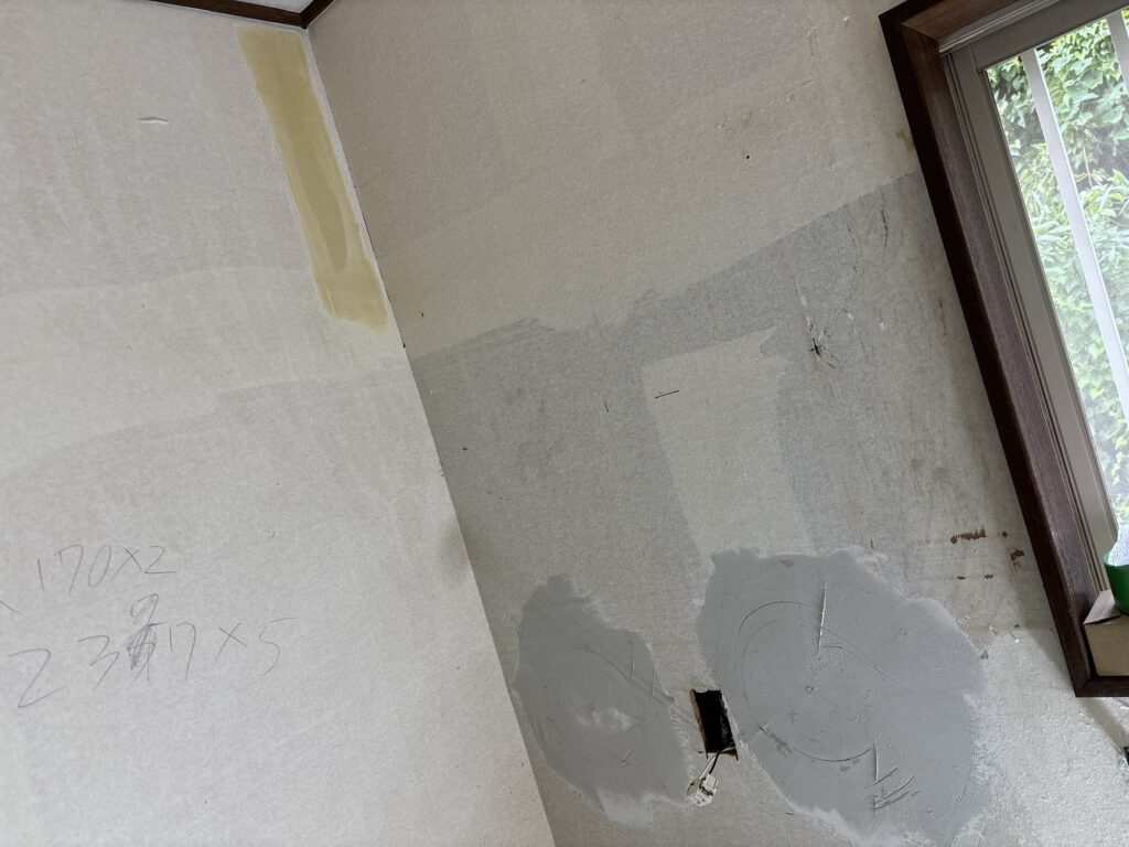 Finishing compound being applied to another wall area while the repaired section dries.