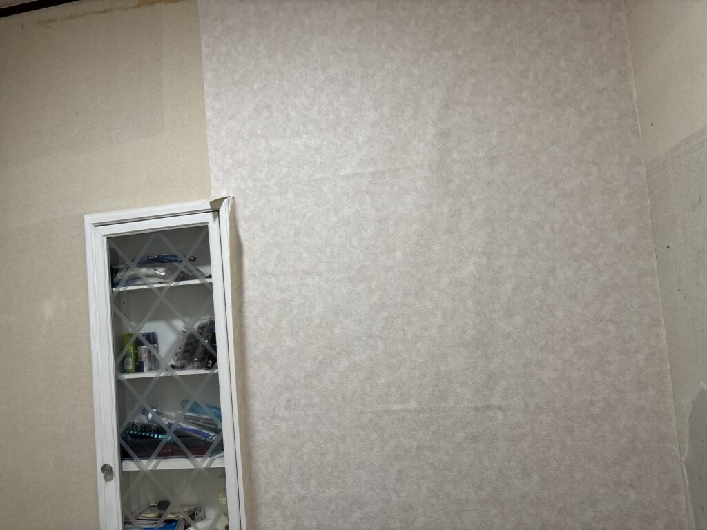 Wallpaper being installed around the cabinet area in the washroom.