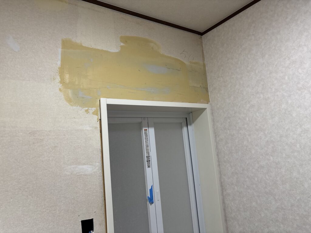 Finishing coat of joint compound applied above the bathroom door frame.