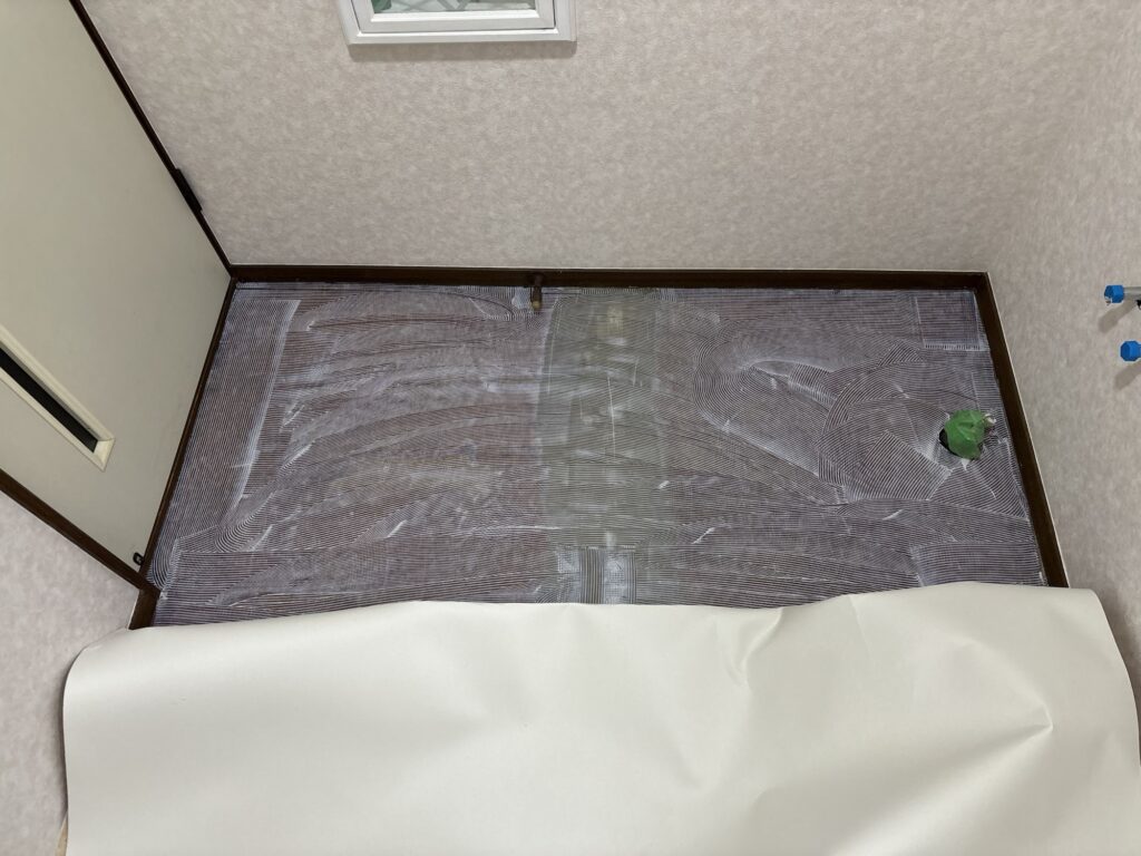 Adhesive applied to half of the washroom floor for cushion flooring installation.