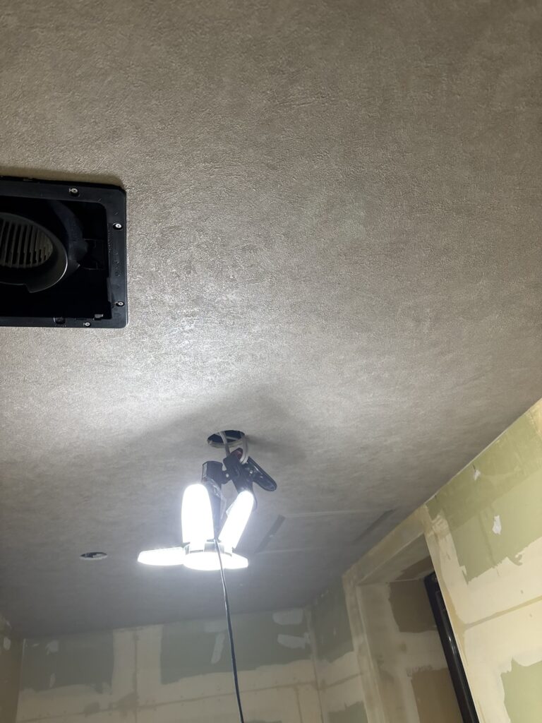 A second view of the finished gray wallpaper on the ceiling of a hotel room.