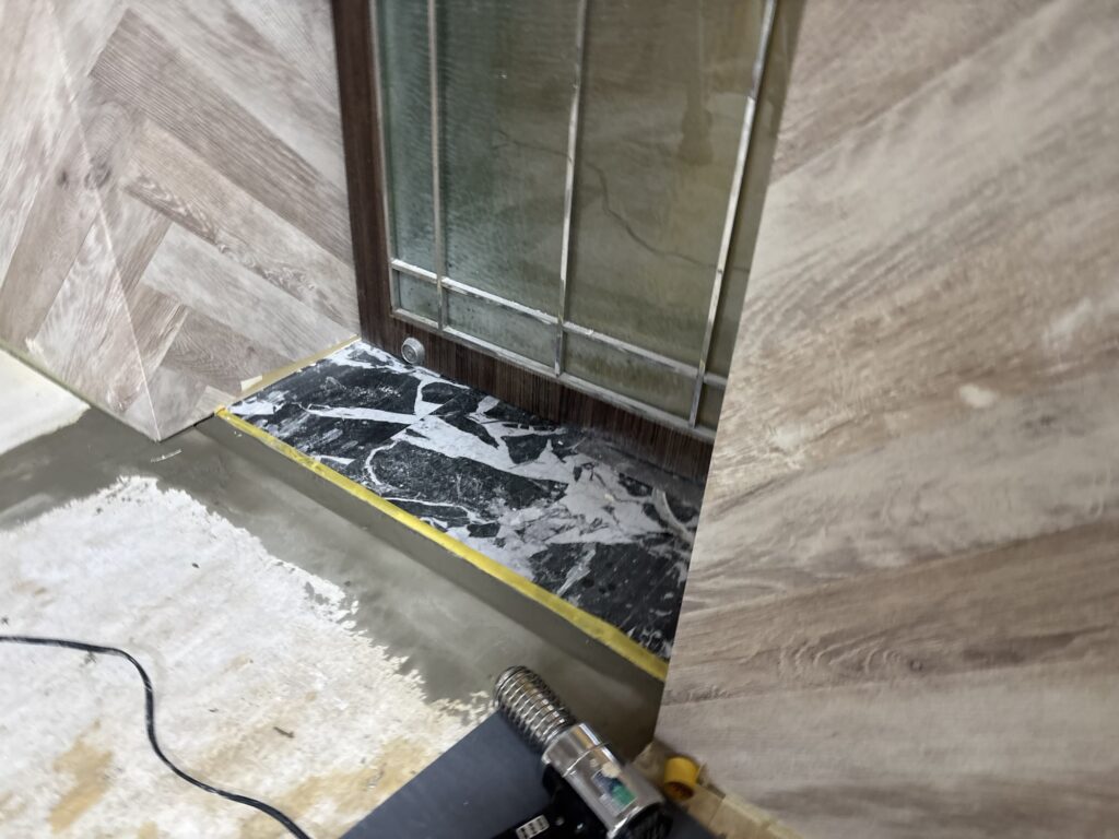 Joint compound being dried with a heat gun at the boundary between existing vinyl floor tiles during renovation.