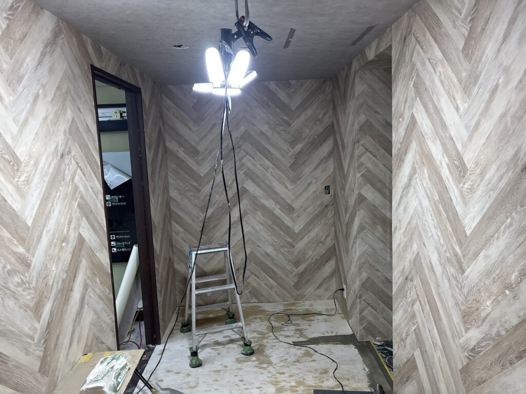 A second view of the completed herringbone-patterned wallpaper in a hotel room.