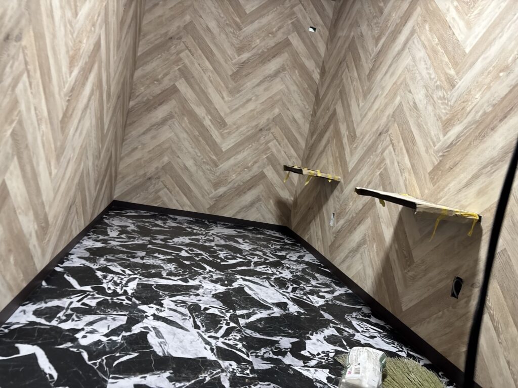 A second view of the finished vinyl tile flooring and soft baseboards in a hotel room.