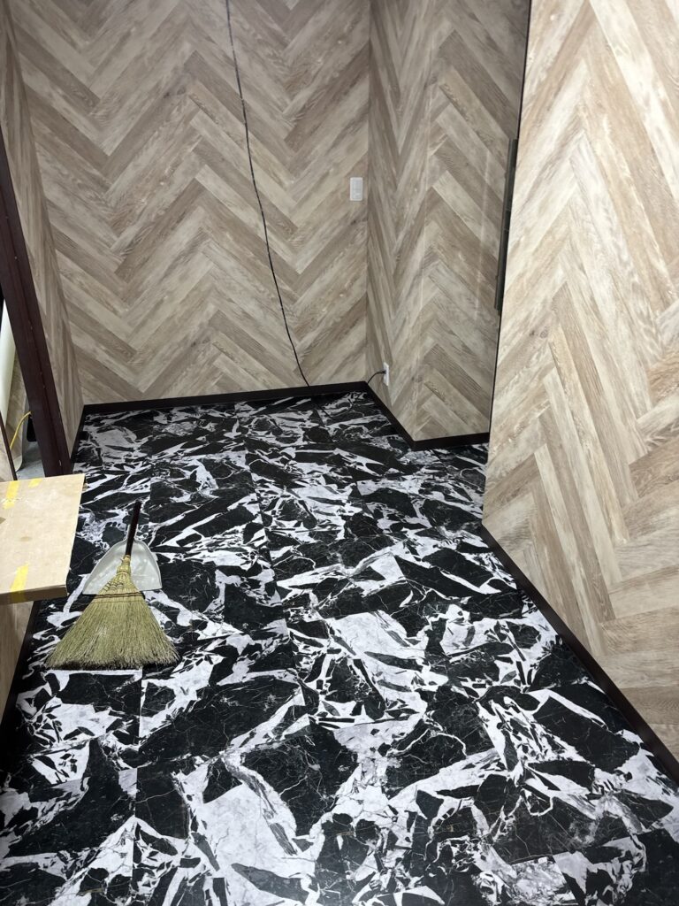 Completed vinyl floor tiles and soft baseboards in a renovated hotel room.