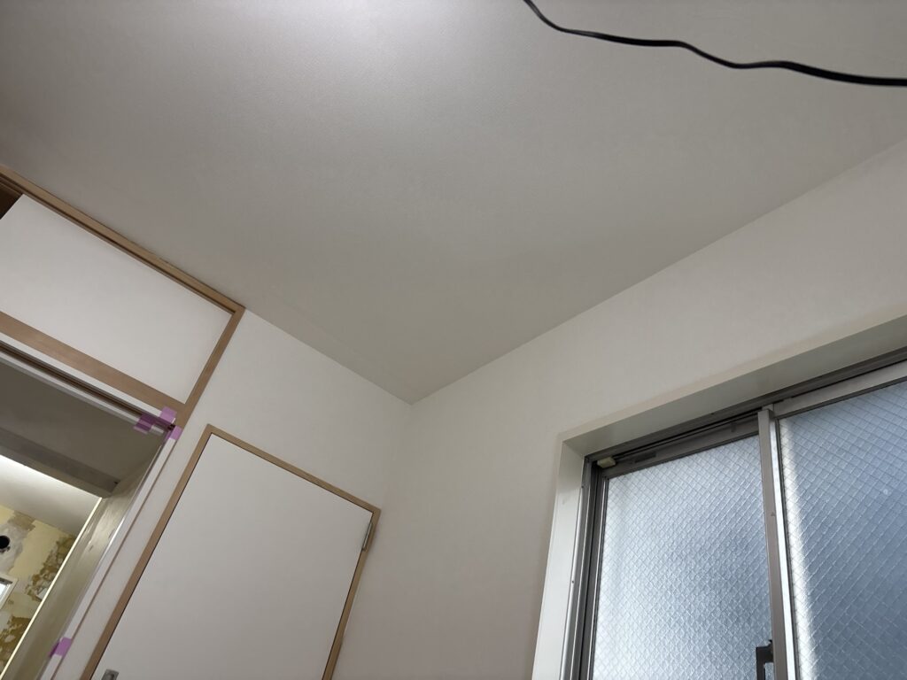 Completed wallpaper installation on the ceiling and walls of a renovated room.