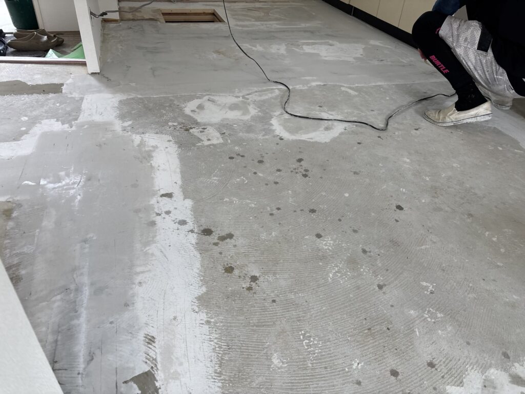 Patching compound applied to an uneven mortar floor before cushion flooring installation.