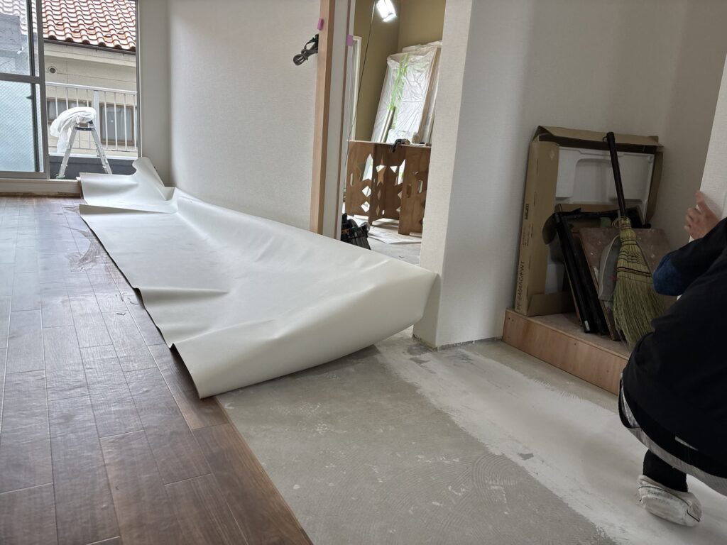 Second sheet of wood-grain cushion flooring being installed in a renovated room.