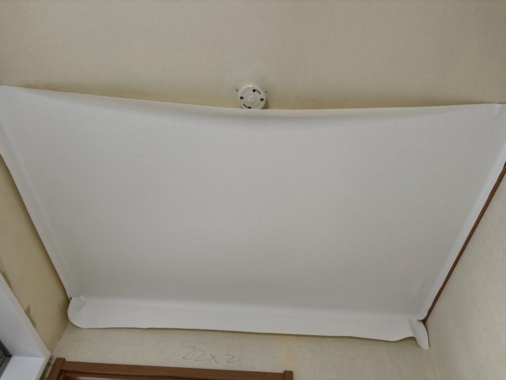 First sheet of wallpaper being installed on the washroom ceiling