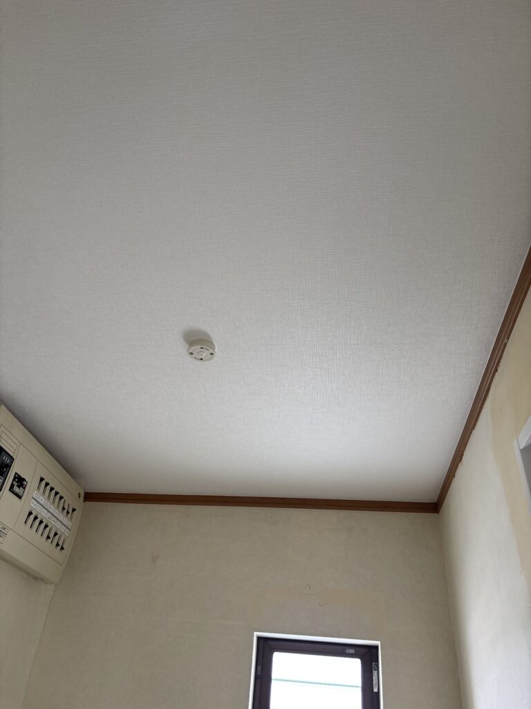 Completed white grid-patterned wallpaper installation on the washroom ceiling