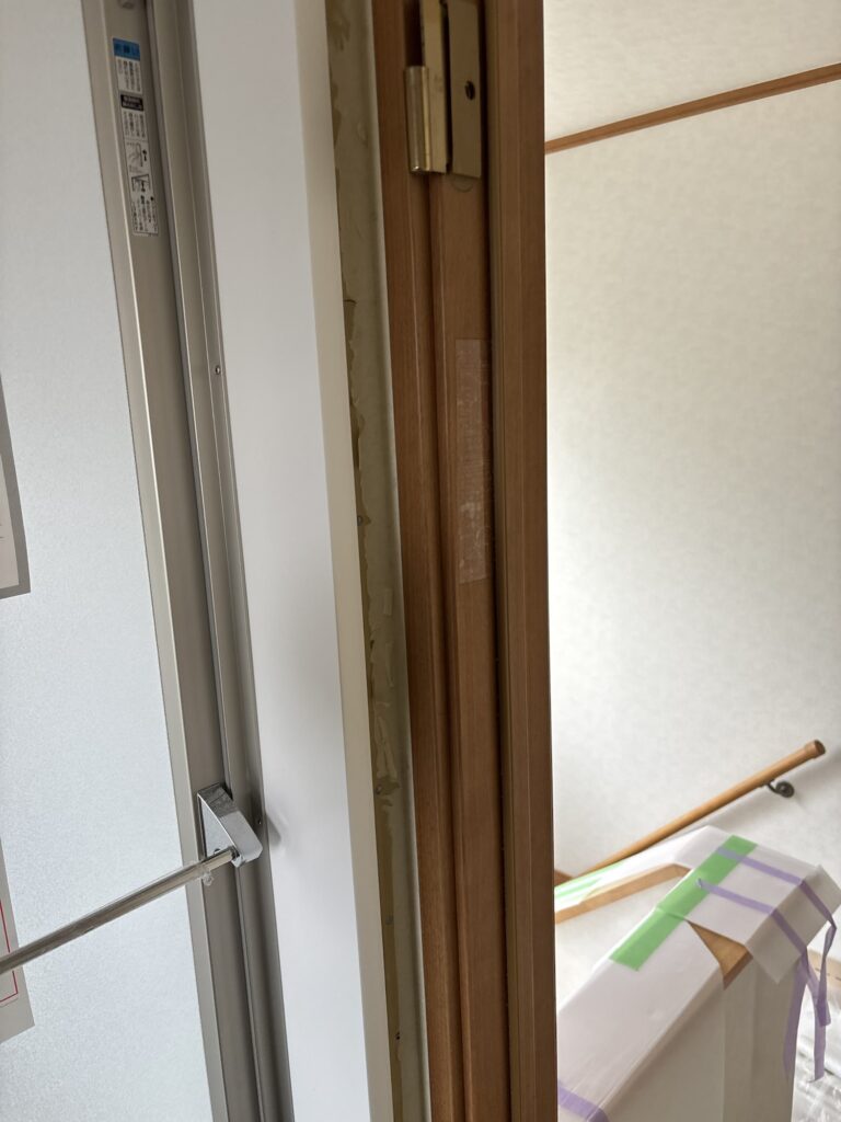 Narrow space between the bathroom and washroom door frames during wallpaper installation