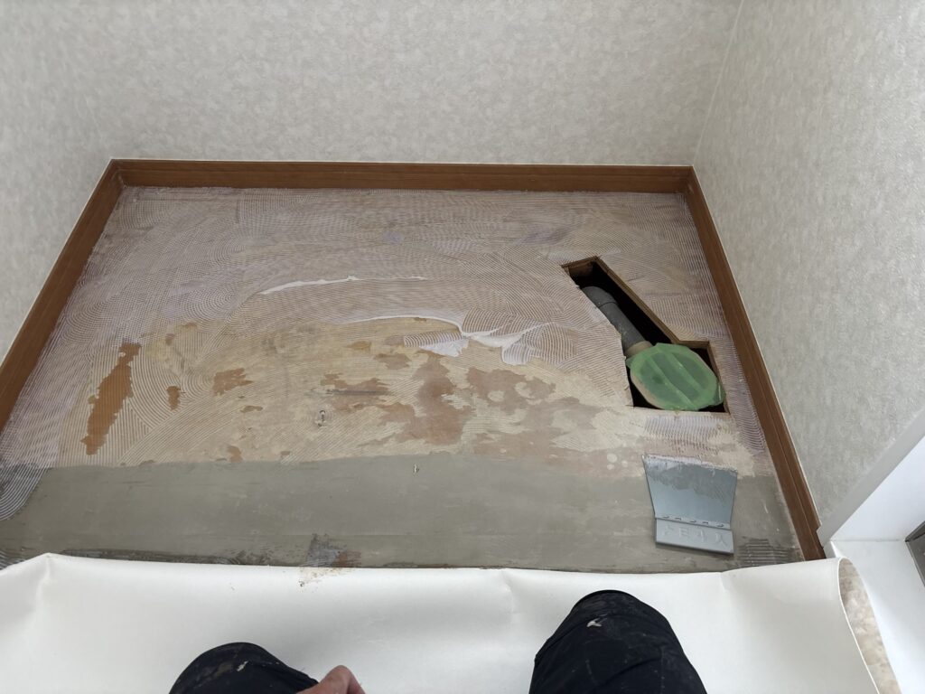 Adhesive being applied to half of the washroom floor before cushion flooring installation