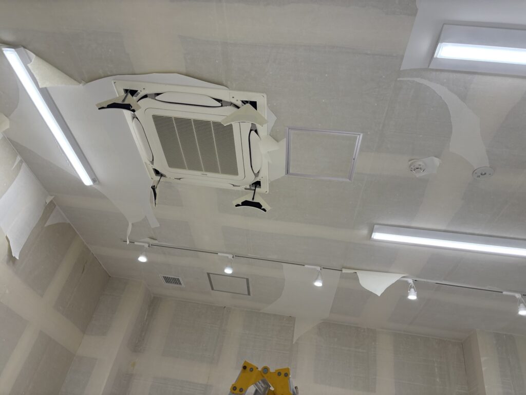Close-up view of a ceiling air conditioner with its cover attached before wallpaper work.