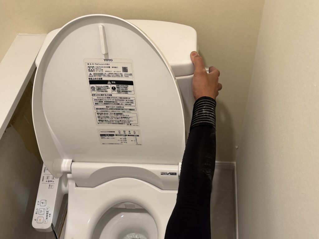 Flushing the toilet to drain water from the tank before removal