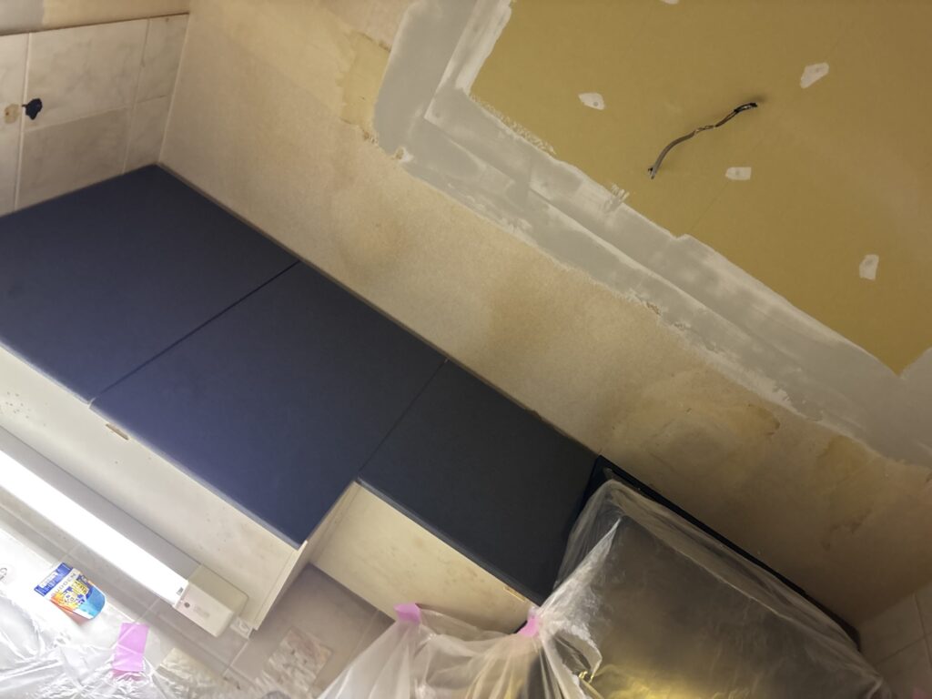 Base coat of joint compound applied to the kitchen ceiling during surface preparation.