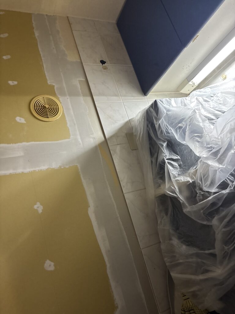 Base coat of joint compound applied to the kitchen wall before wallpaper installation.
