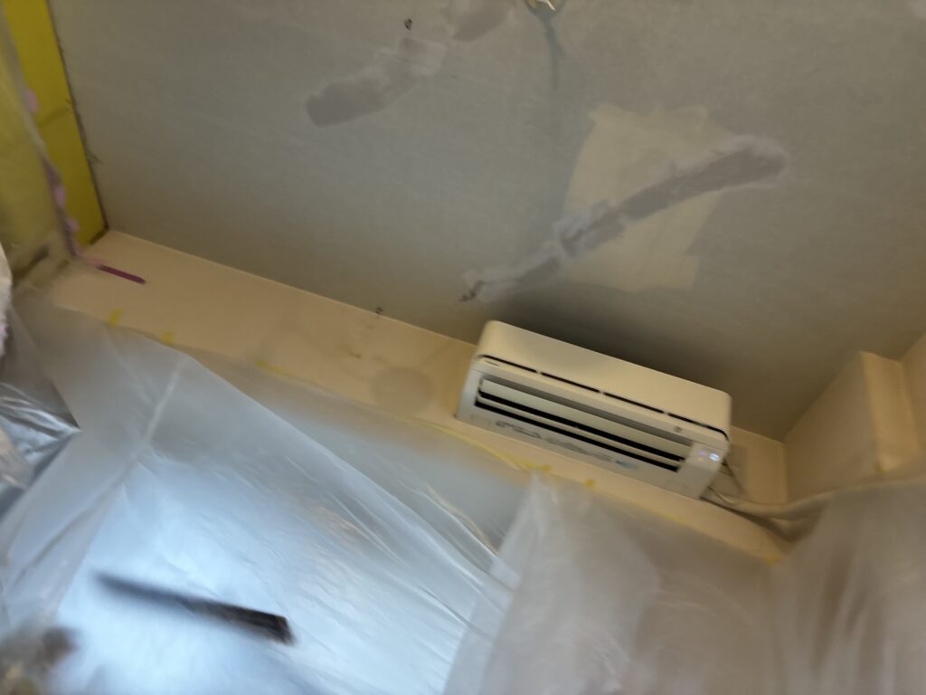 Living room ceiling with a base coat of joint compound applied before wallpaper installation.