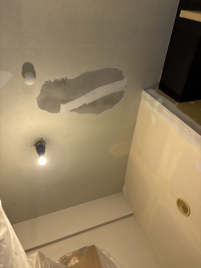 A crack in the living room mortar ceiling being repaired with joint compound before wallpaper installation.